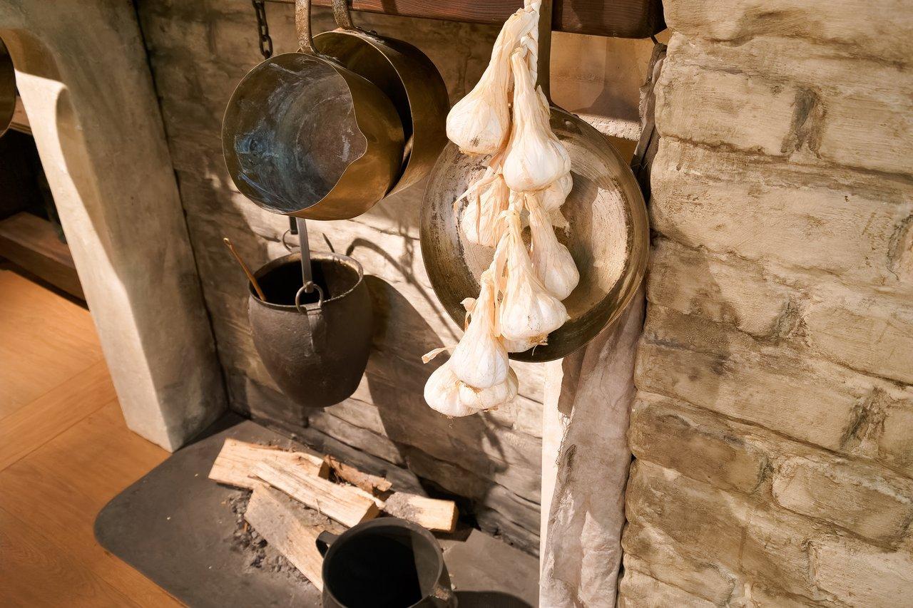 Cuisine rustique et durable avec ail suspendu, murs en pierre et accents en bois pour une ambiance chaleureuse.