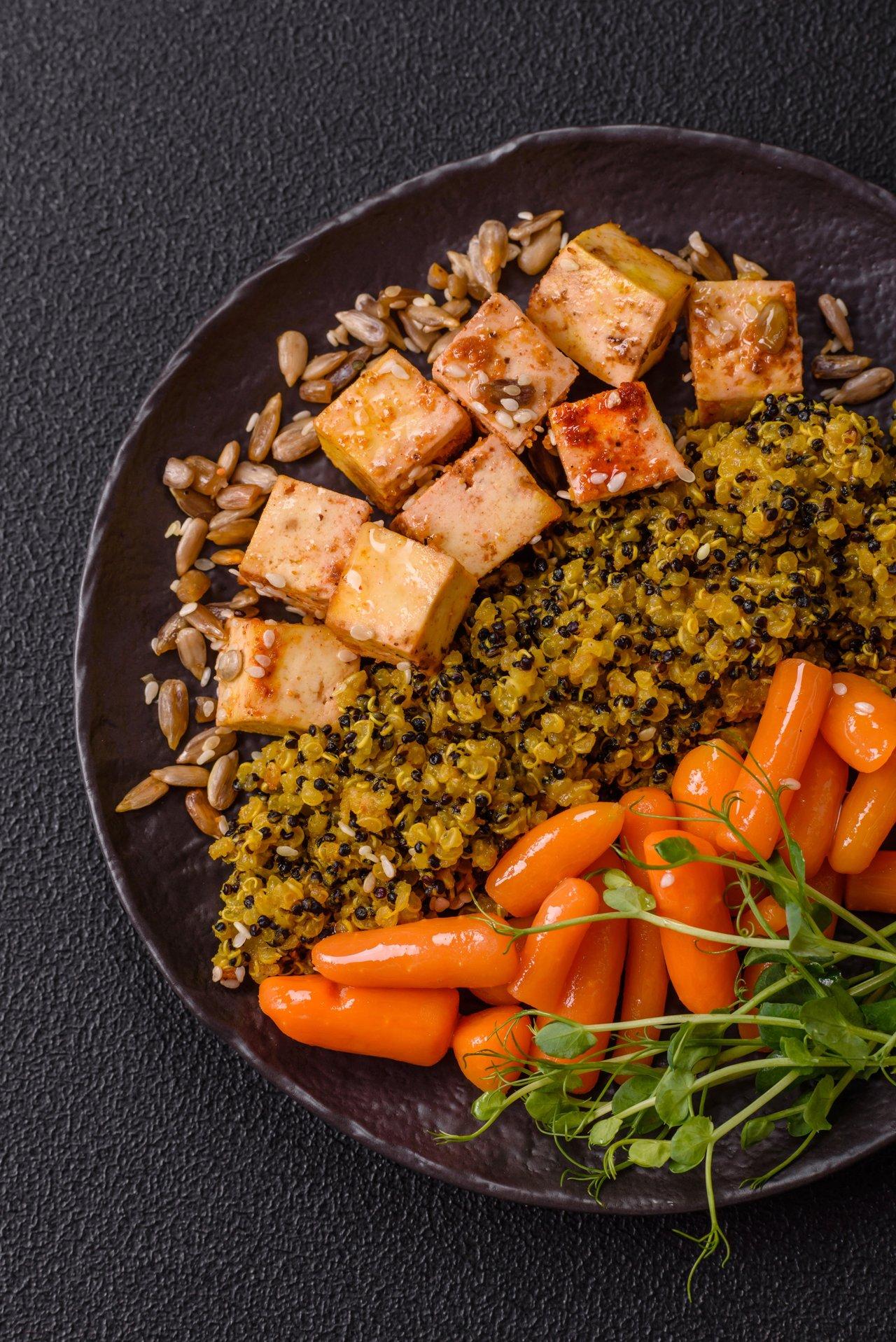Un repas végétal équilibré avec quinoa, tofu, légumes vapeur et graines pour un mode de vie durable.